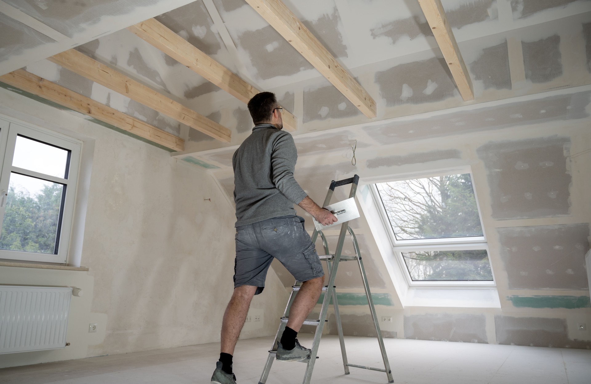 Man plastering drywall in a private house.